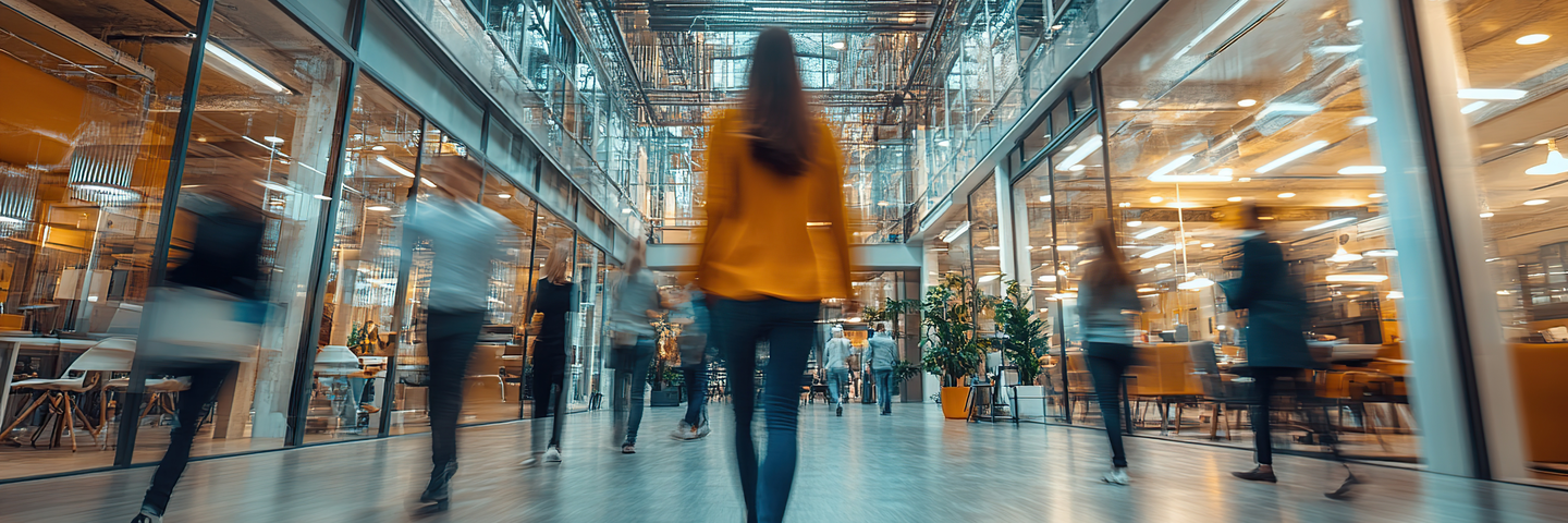 Woman walking through busy modern office building atrium.